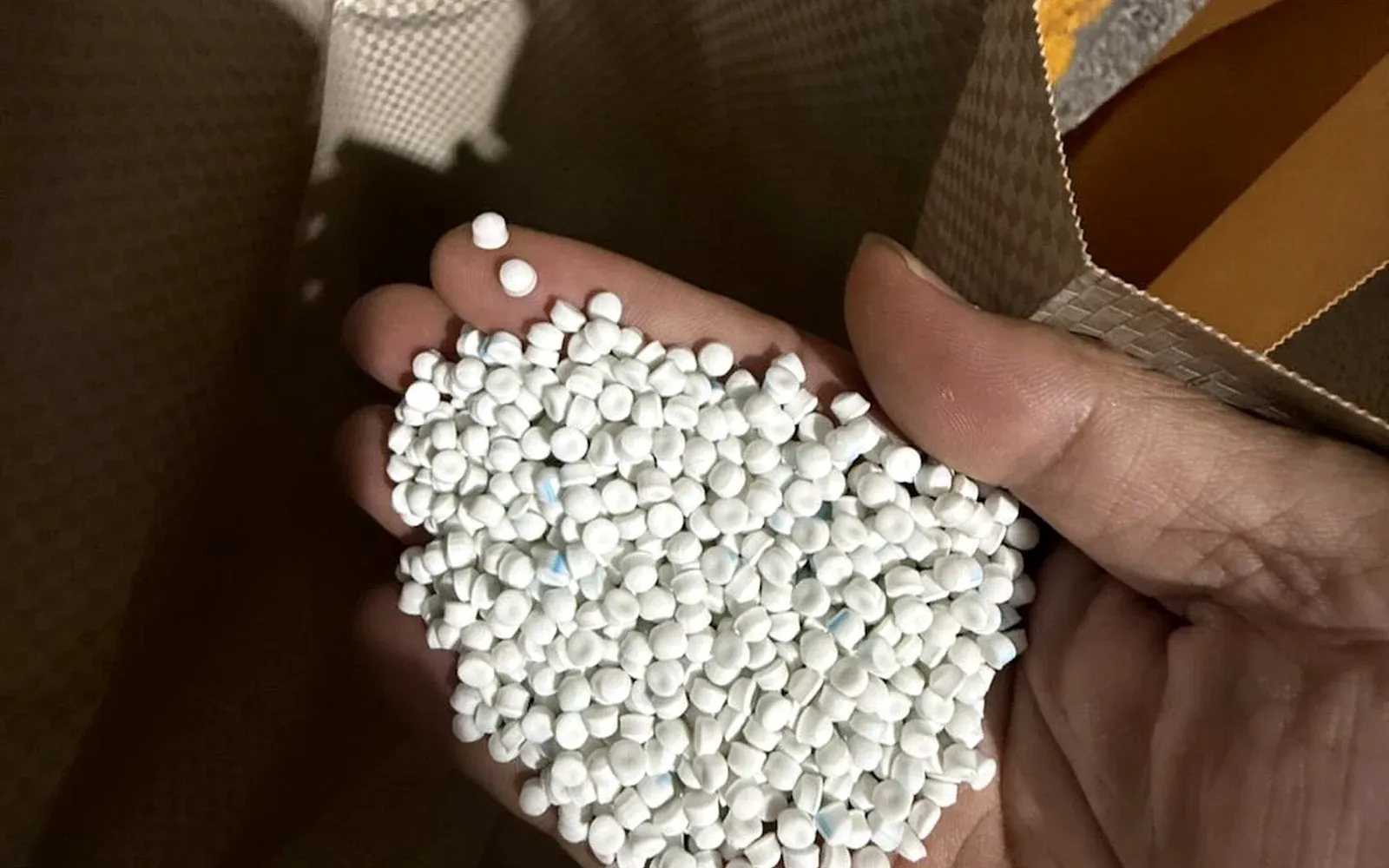 Hand holding white HZD1610 heat shrink tube master compound pellets